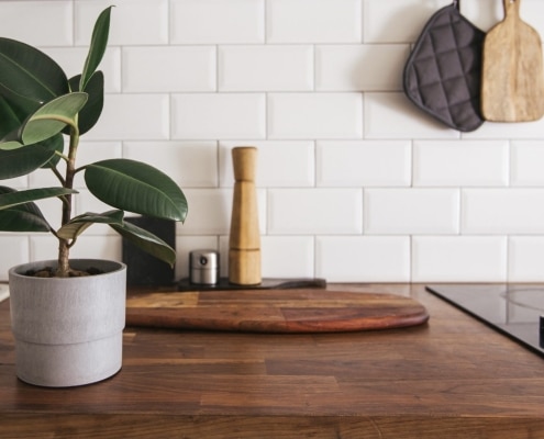 Plan de travail en bois dans une cuisine moderne avec crédence en carreaux blancs, plante verte et accessoire de cuisine