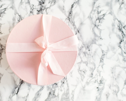 Boîte cadeau rose poudré sur arrière plan en marbre noir et blanc